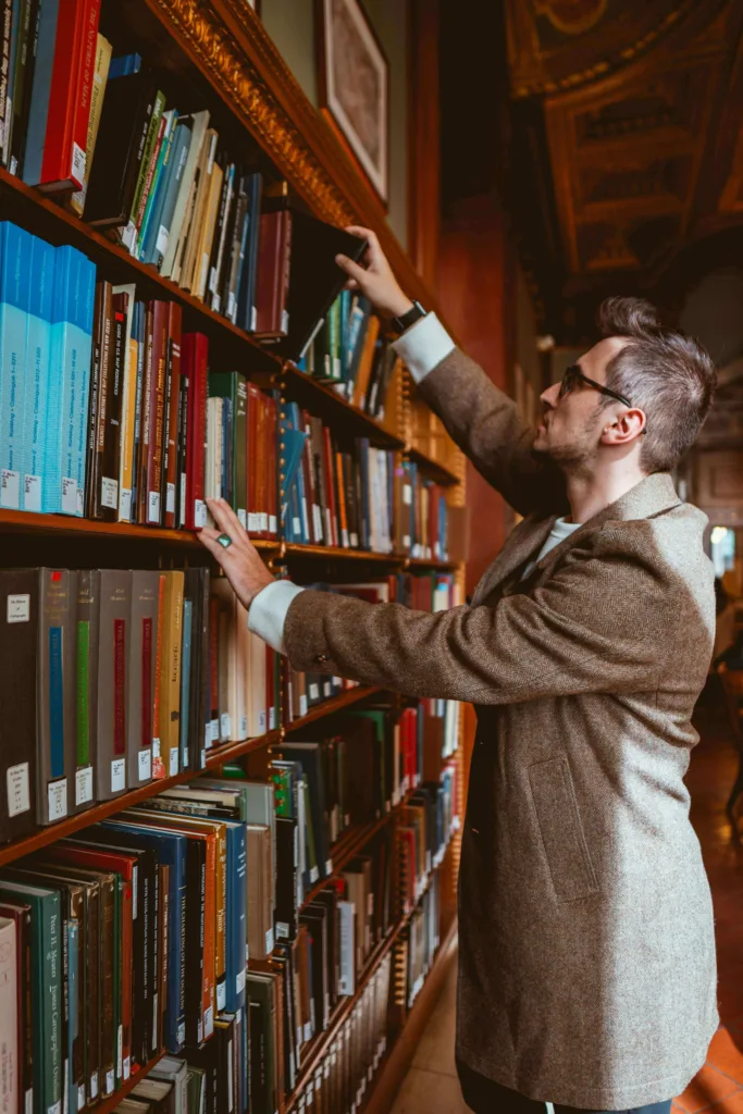 A guy searching book in bookshelves.